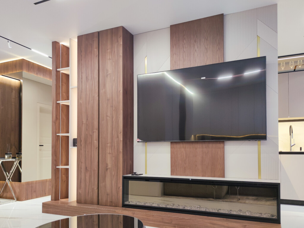 ТВ на шпонованій панелі й електрокамін у чорній рамі DreamHouse.