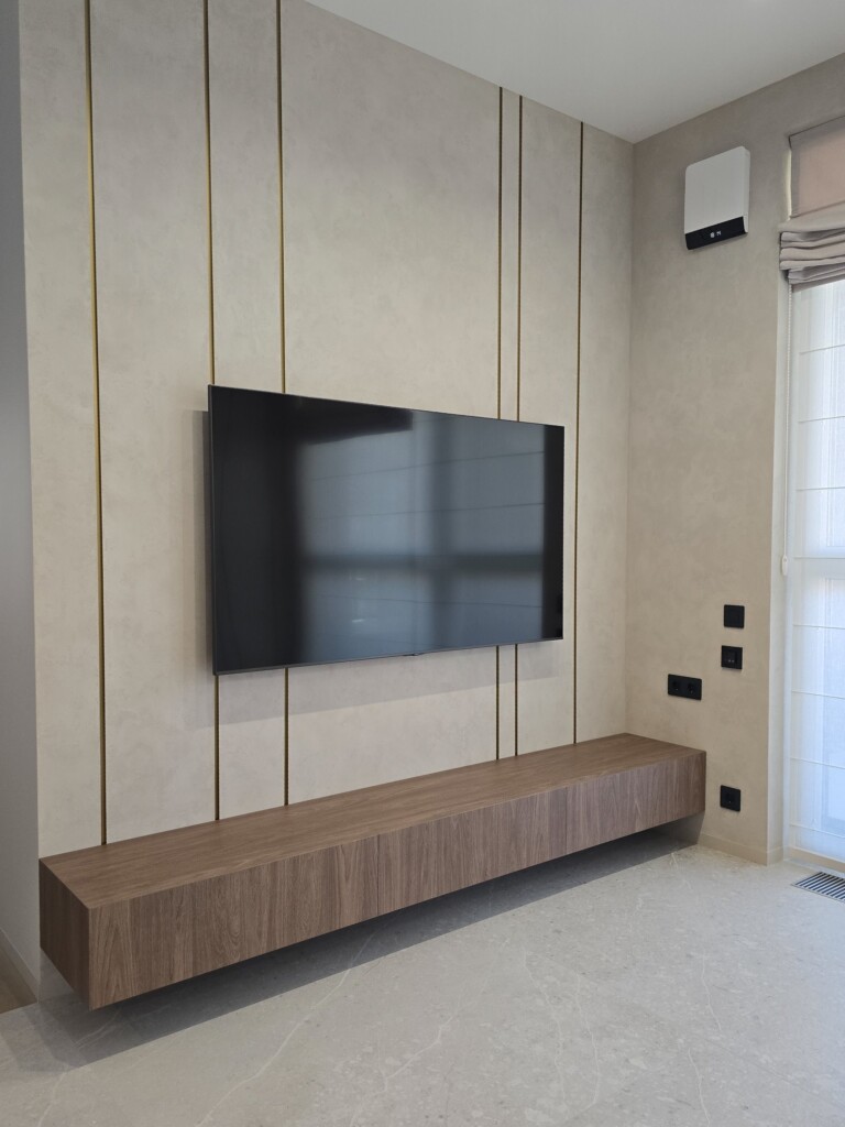 Підвісна тумба під ТВ у вітальні на тлі панелі з латунними вставками DreamHouse.